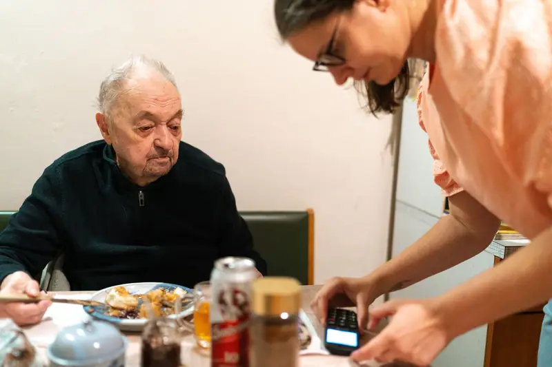 A caregiver bringing an older man his lunch